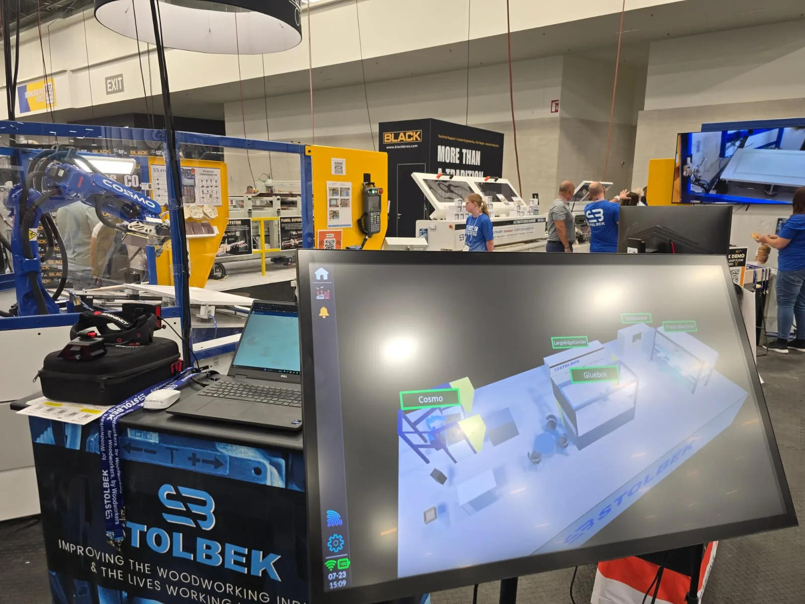 Stolbek standında OnoTwin — ekranda ahşap işleme hattının dijital ikizi, arkada robot hücresi